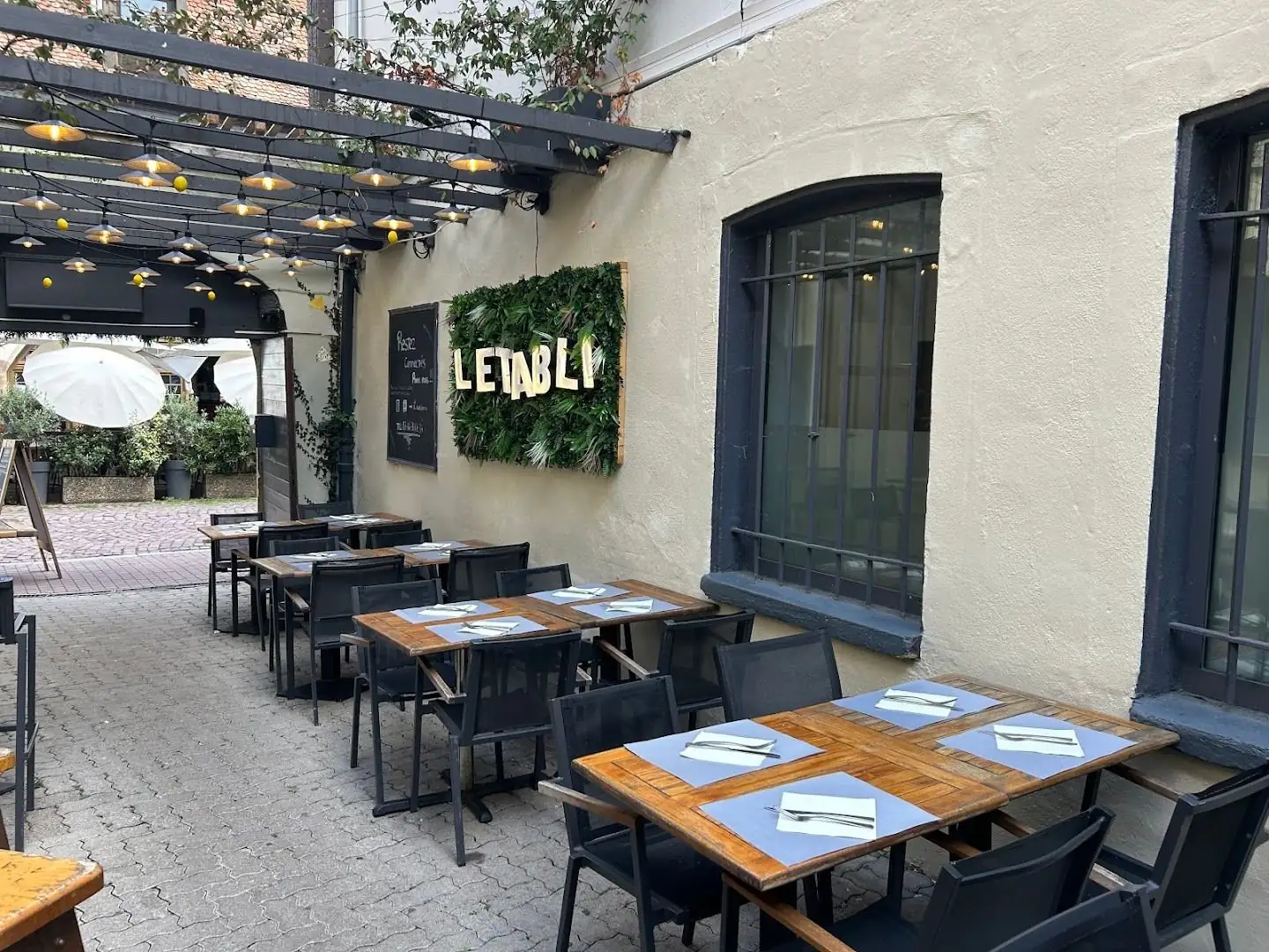 La terrasse dans la cour de L'Etabli, tables en bois sous la pergola